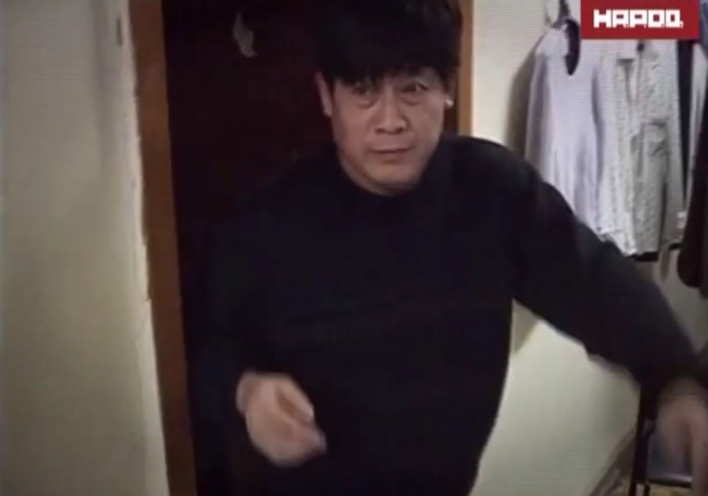 An Asian man leaving an apartment